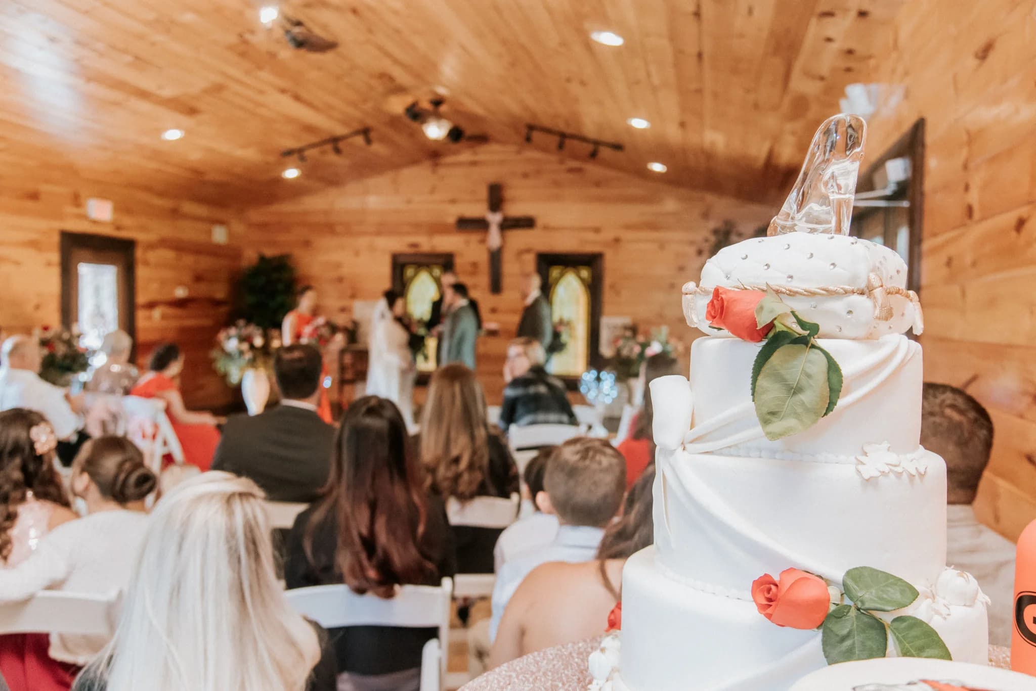 Tiered wedding cake with glass slipper topper in a rustic wood chapel at Moose Hollow Lodge in Pigeon Forge
