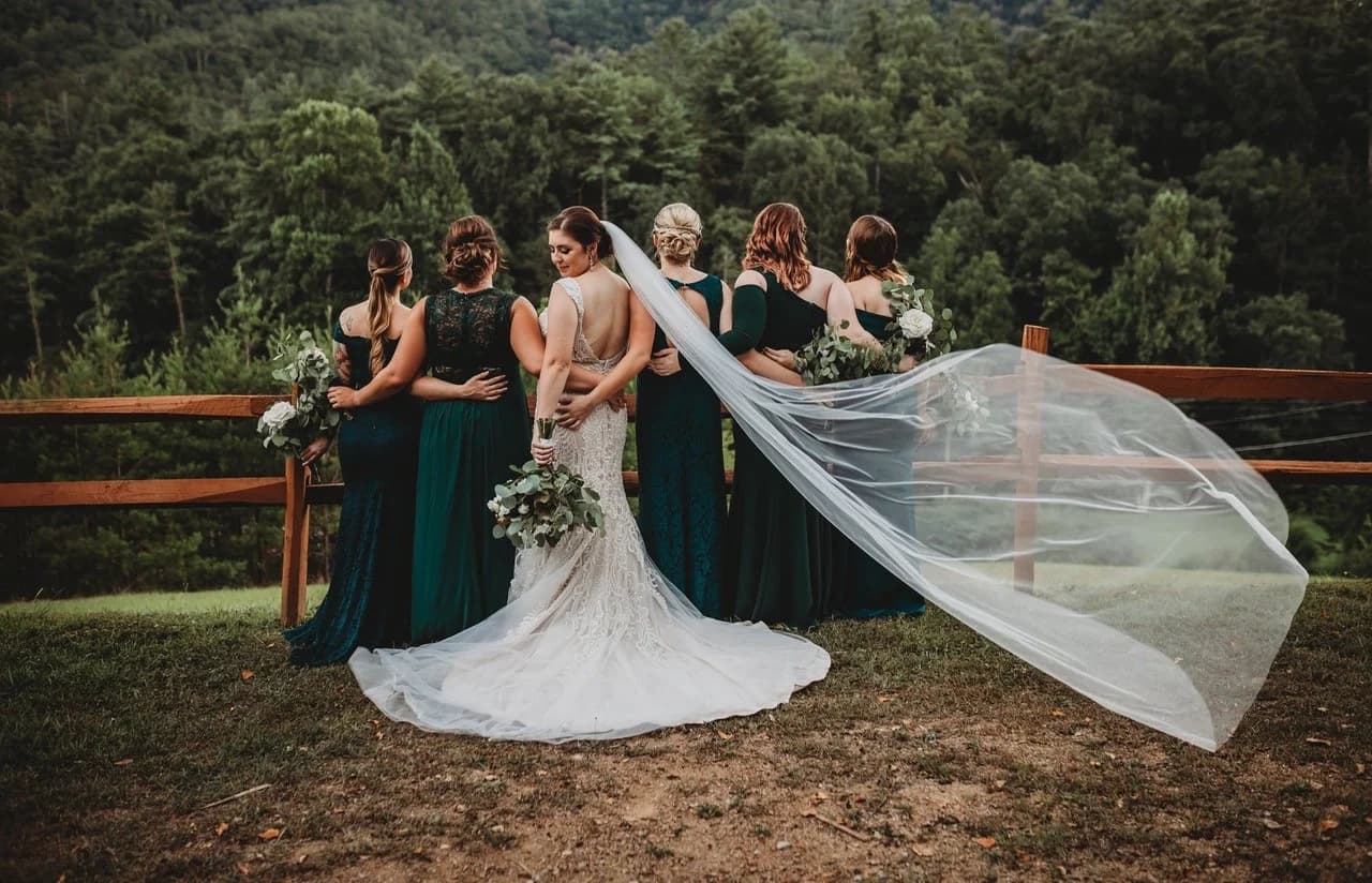 Moose Hollow Lodge's outdoor event space with a dense green forest backdrop and a rustic split-rail fence.