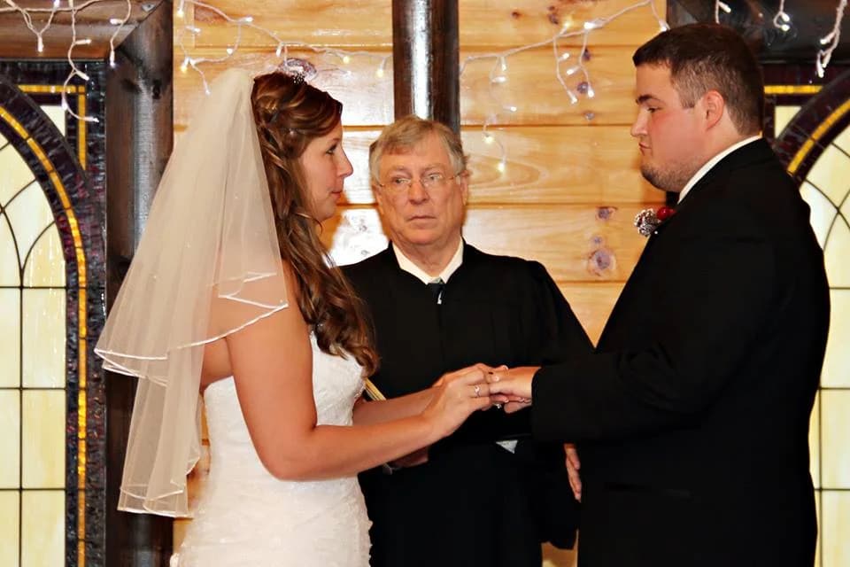Couple exchanging wedding rings in a rustic wooden chapel at Moose Hollow Lodge in Pigeon Forge