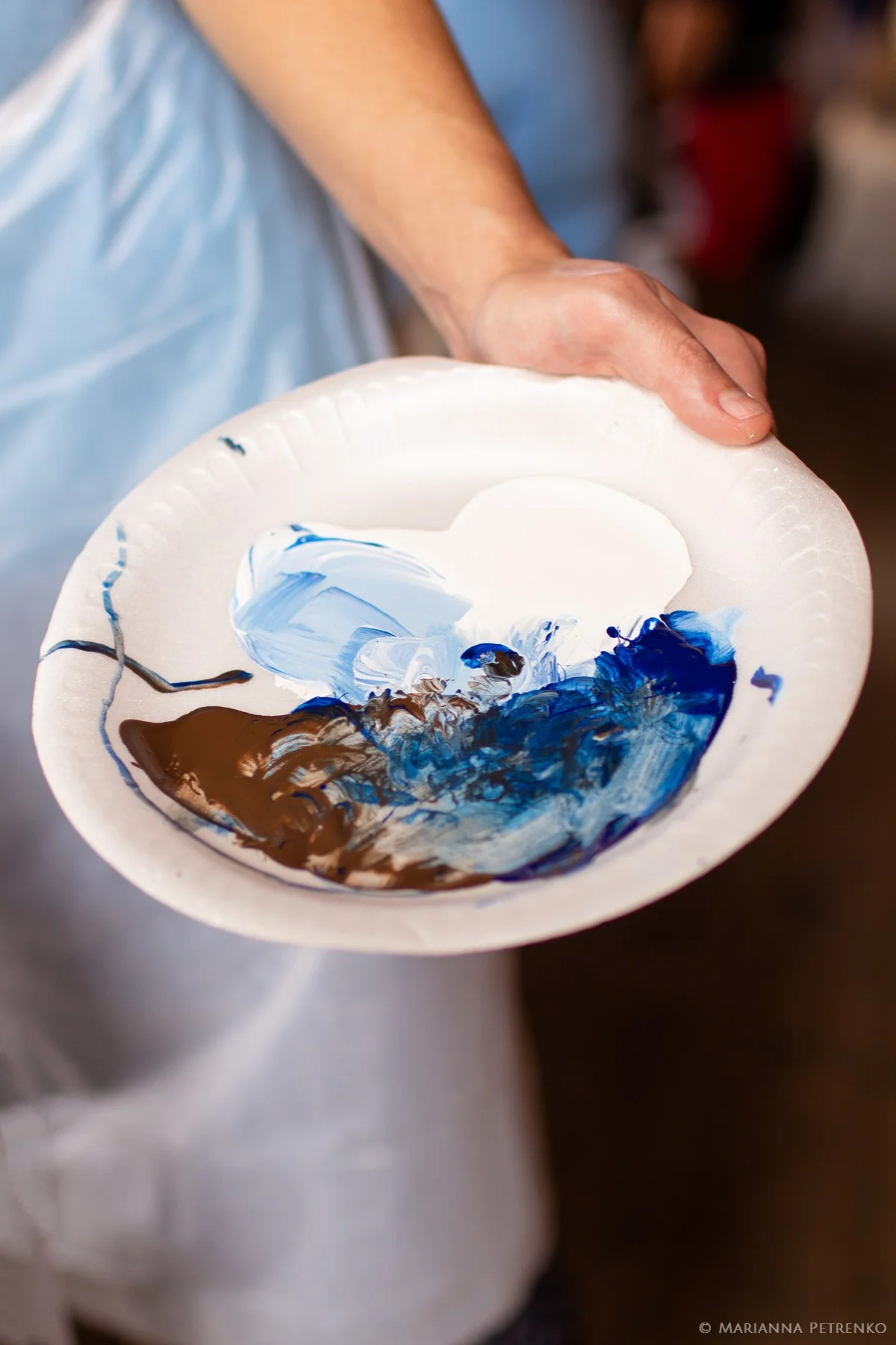 Person holding blue and white paint on a plate for wedding activity at Moose Hollow Lodge in Pigeon Forge