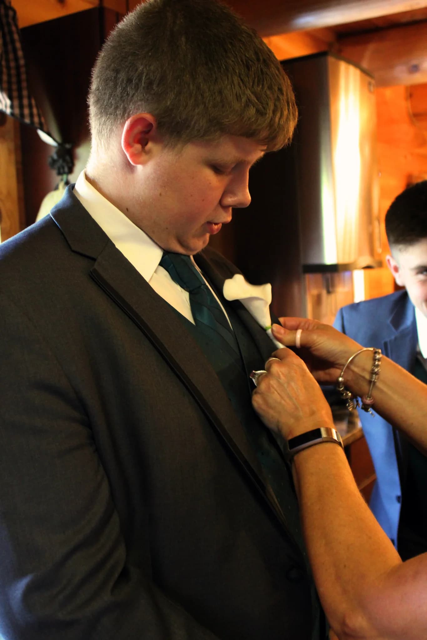 Groom in navy suit receiving a white calla lily boutonniere at Moose Hollow Lodge in Pigeon Forge