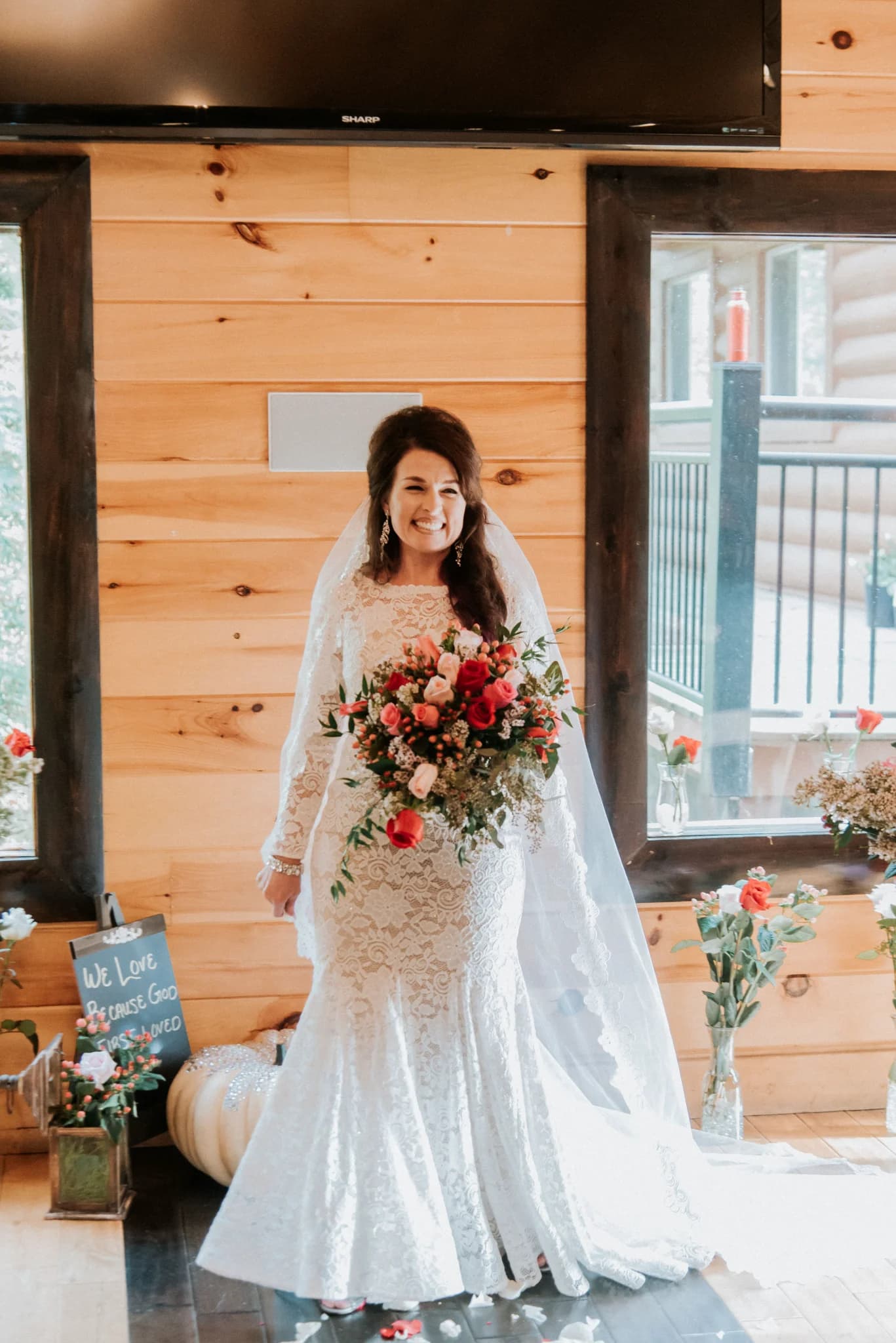 Rustic lodge interior with wood plank walls, dark window frames, and floral wedding decor.
