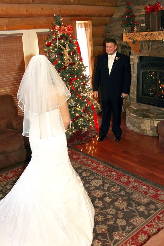 Bride and groom by a Christmas tree and stone fireplace at Moose Hollow Lodge in Pigeon Forge