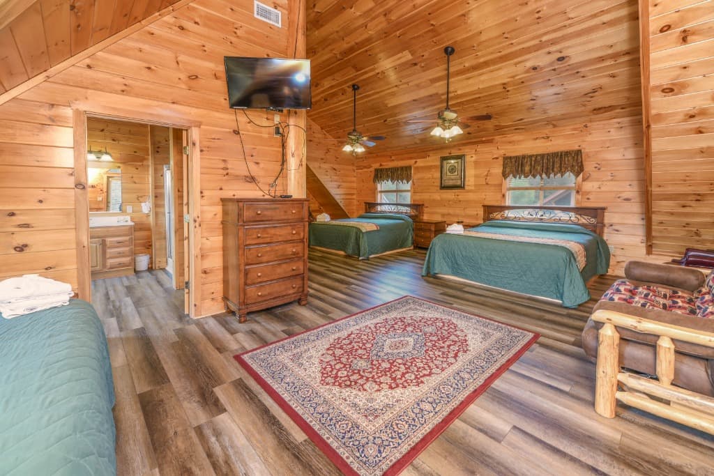 Rustic cabin bedroom with two beds and vaulted wood ceilings at Moose Hollow Lodge in Sevierville