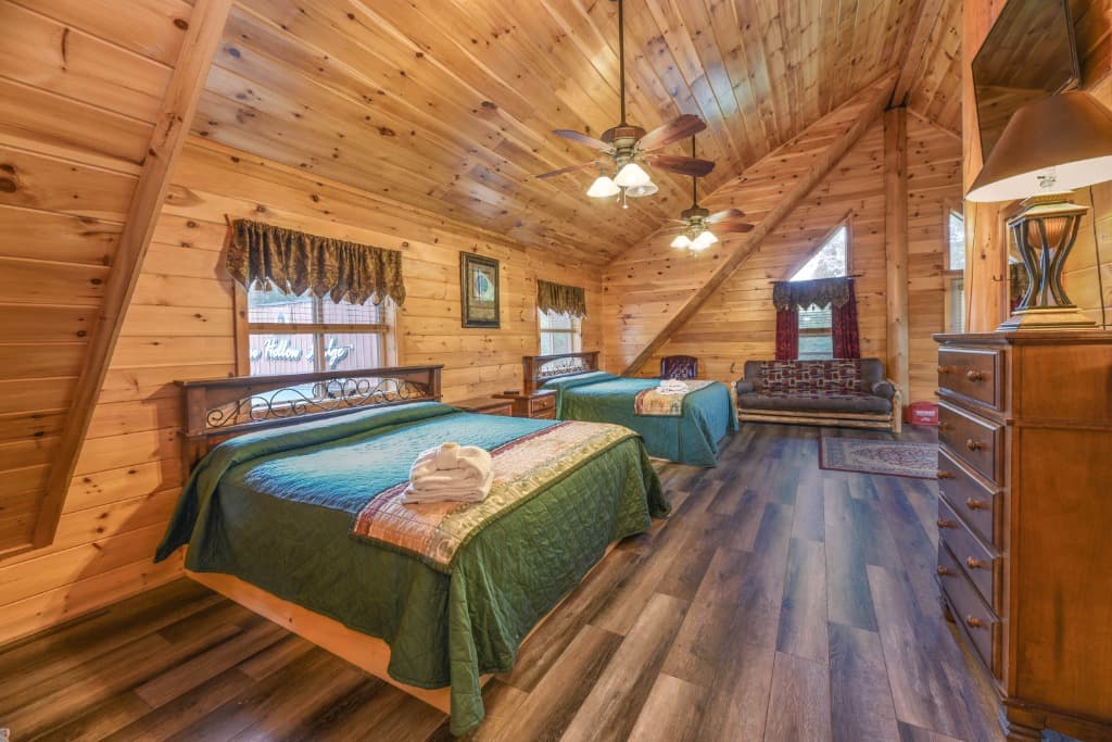 Spacious wood-paneled bedroom with two beds and vaulted ceilings at Moose Hollow Lodge in Sevierville