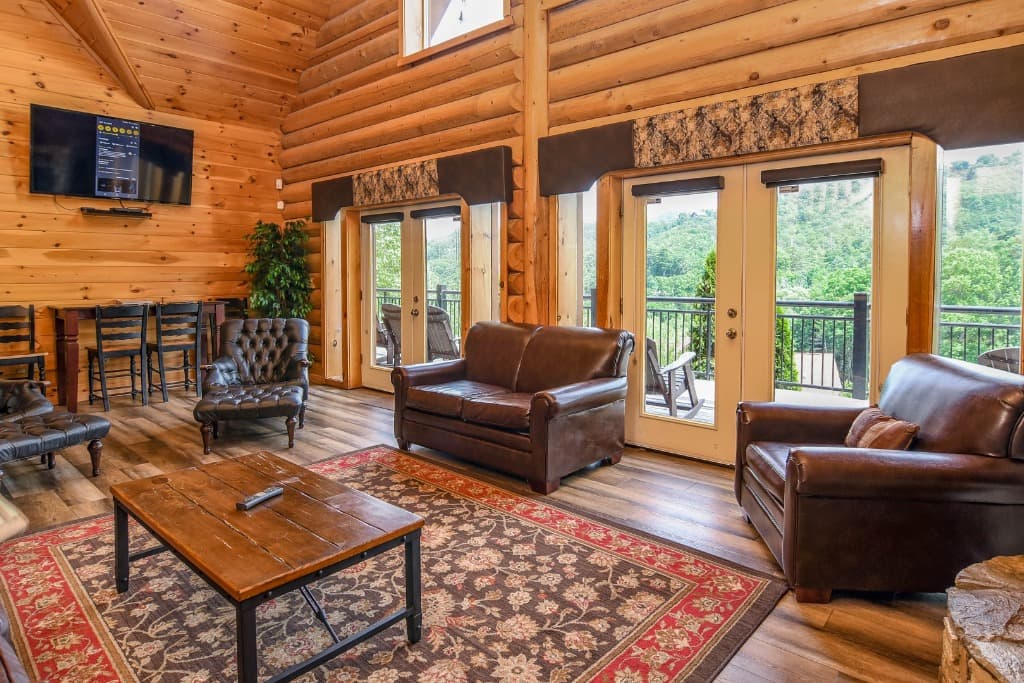 Rustic log cabin living room with leather seating and deck views at Moose Hollow Lodge in Sevierville