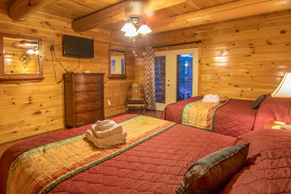 Rustic bedroom with two queen beds and balcony access at Moose Hollow Lodge in Sevierville