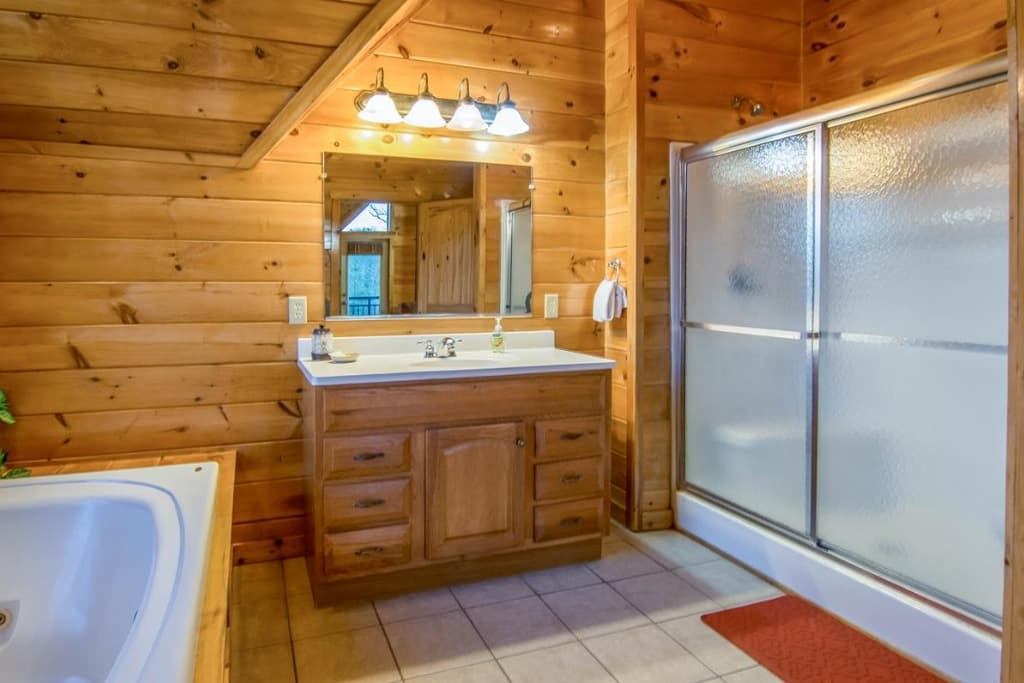 Rustic wood-paneled bathroom with single vanity, shower, and tub at Moose Hollow Lodge in Sevierville