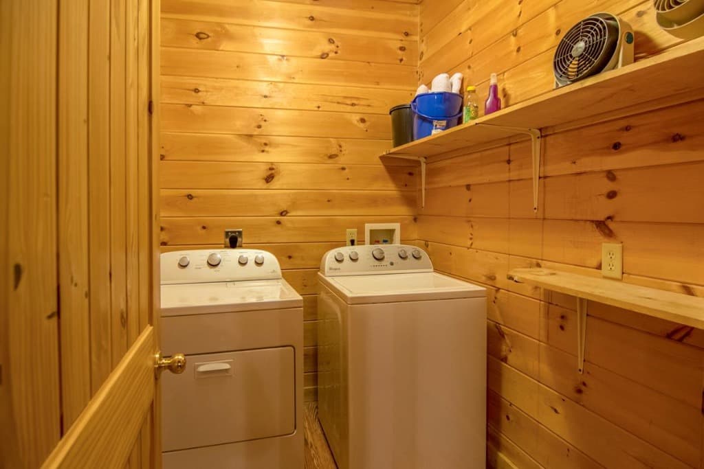 Wood-paneled laundry room with washer, dryer, and shelving at Moose Hollow Lodge in Sevierville.