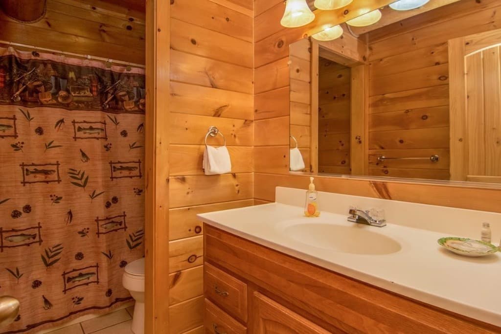 Rustic wood-paneled bathroom with a large vanity and mirror at Moose Hollow Lodge in Sevierville.