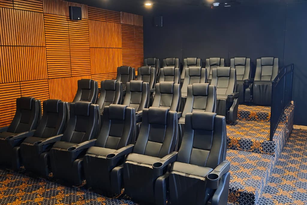 Spacious home theater room with tiered black leather reclining seats, wood paneling. Ideal for vacation rental entertainment.